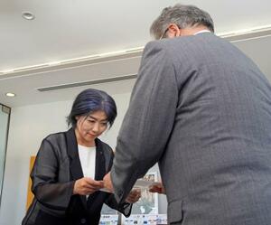 静岡県伊東市議会の中島弘道議長(右)から証人尋問に出席するよう求める文書を受け取る田久保真紀市長=22日午前、伊東市役所