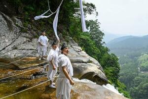 「那智の滝」の上に架かるしめ縄を張り替える熊野那智大社の神職=9日午前、和歌山県那智勝浦町