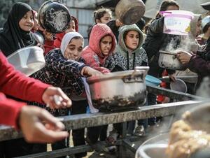 　１４日、パレスチナ自治区ガザ中部で、配給の食事を受け取るパレスチナ人（ゲッティ＝共同）