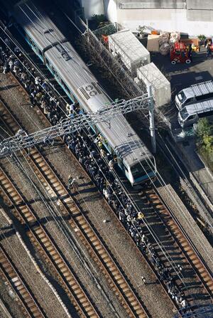 高輪ゲートウェイ-田町間で停車したJR京浜東北線の車両から降りて線路を歩く乗客=16日午前9時44分、東京都港区(共同通信社ヘリから)