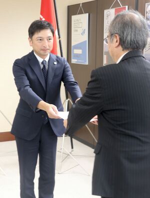 花角英世知事に包括外部監査の基本計画書を手渡す外部監査人の大田陸介氏(左)=8月19日、県庁