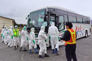 防疫作業のため養鶏場に向かう作業員ら＝９日午前８時前、胎内市