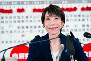 　当確者の名前のバラの前で、メディアのインタビューに笑顔で答える自民党総裁の高市首相＝８日午後１０時３分、東京・永田町の党本部