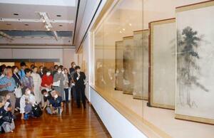 再開する石川県七尾美術館の内覧会で、学芸員から国宝「松林図屏風」の説明を聞く参加者=19日午後、七尾市