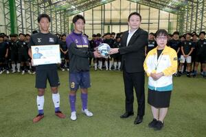 明治安田生命保険からボールを受け取る上越高サッカー部の松澤煌成主将(左から2人目)=上越市寺町3