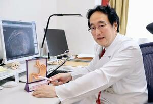 胃の模型を使い、スイス菌の感染部位を示す杏林大の徳永健吾教授=東京都三鷹市