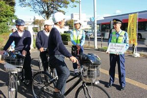 「転倒予防の日」に合わせ、自転車利用者にヘルメットの着用を呼びかける警察官ら=新潟市中央区