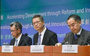 記者会見で財政予算案について説明する陳茂波財政官(中央)=2月、香港