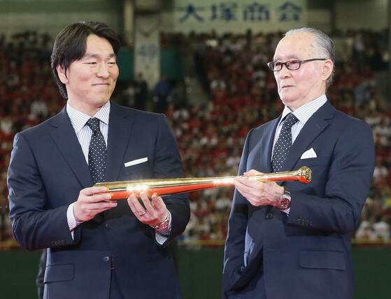 ２０１３年５月、国民栄誉賞の授与式で金色のバットを贈呈された長嶋茂雄さん（右）と、手を添える松井秀喜さん