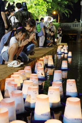 長岡空襲で多くの人が逃げ命を落とした柿川で、犠牲者を悼み平和を願う灯籠を流す人たち＝１日、長岡市旭町２