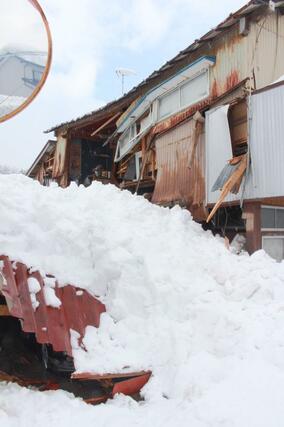 雪の重みで倒れた車庫。隣の住家部分も損壊していた＝３日、柏崎市与板