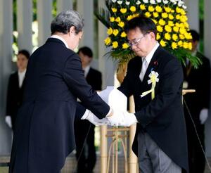 　千鳥ケ淵戦没者墓苑で開かれた拝礼式で、新たに納骨する遺骨を受け取る上野厚労相＝２５日午後、東京都千代田区