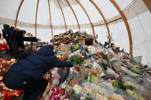 9日、スイス南部バレー州クランモンタナで、火災の犠牲者を追悼する式典で花を手向ける参列者(ゲッティ=共同)