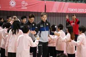 ろう学校の子どもたちとハイタッチしながら入場する、バドミントン日本代表の沼倉昌明選手（中央）ら＝２５日、東京都調布市の京王アリーナＴＯＫＹＯ