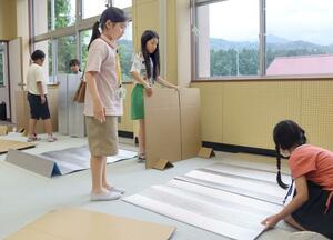 段ボールの仕切りを用いて就寝スペースを整える子どもたち=新発田市上赤谷