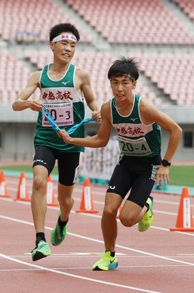 男子 中越の3区丸山展(左)がトップで4区星野愁にタスキを渡す=新潟市中央区
