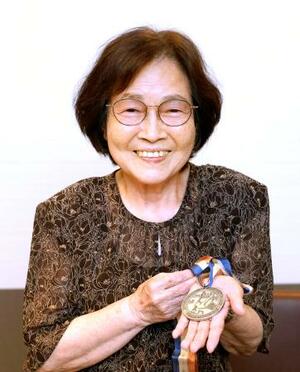 　デフリンピックの１９６５年ワシントン大会卓球で獲得した銀メダルを手にする鈴木リヲ子さん＝５日、東京都東大和市