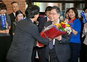 ノーベル生理学・医学賞の受賞決定から一夜明け、大阪大の熊ノ郷淳学長(左)から花束を受け取る坂口志文特任教授=7日朝、大阪府吹田市