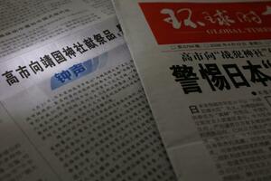 　靖国神社に「真榊」を奉納した高市首相を批判する評論を掲載した、２２日付の中国共産党機関紙、人民日報。右は１面トップで報じる環球時報（共同）