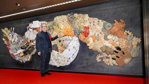 原画や監修を手がけた陶板製の大型レリーフと写真に納まる漫画家大友克洋さん=15日午前、東京メトロ銀座駅構内