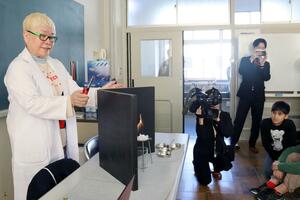メタンハイドレートの燃焼実験をする東京海洋大特任准教授の青山千春さん(左)=上越市大潟区の大潟町小学校