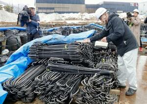 「クリアランス金属」を再利用した鉄筋の放射線量を測定する担当者(右)=18日午後、福井県南越前町