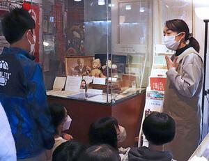 刈羽小6年生に向けて青い目の人形の歴史を説明する痴娯の家館長の牧口明子さん=柏崎市青海川