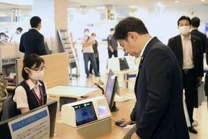 スマホ保険証を使った受け付けを体験する福岡厚労相(手前右)=7月、東京都目黒区の東京医療センター