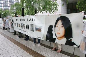 タペストリーを掲げて拉致問題の早期解決を訴える「あさがおの会」のメンバーら=10日、東京・永田町