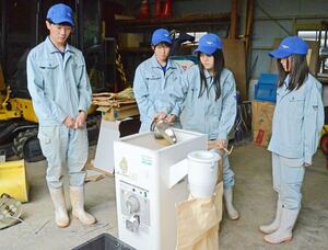 贈られた精米機を使う十日町総合高校の生徒たち=十日町市高山4