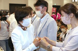 敗戦の弁を述べた後、硬い表情のまま支持者とグータッチを交わす森裕子さん=7月10日午後10時前、新潟市中央区