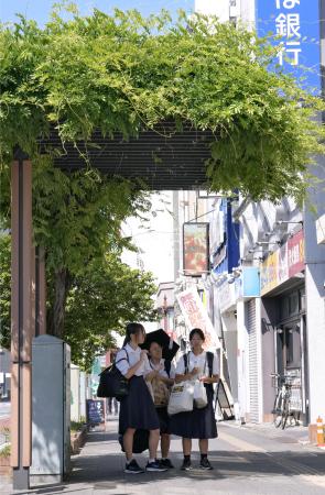 厳しい暑さとなり日陰で信号待ちする人たち=30日午後、埼玉県熊谷市