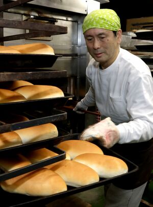 焼き上がったコッペパンを並べる小竹孝雄さん＝上越市南高田町