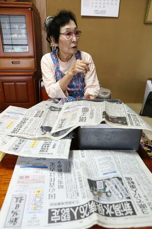新潟水俣病に関する記事を広げる小武節子さん。第2次訴訟提起時からスクラップしている=新潟市東区