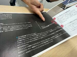 「36カ月プロジェクト」のパンフレットを示し取材に応じる事業所利用者の男性=4月、大阪市中央区
