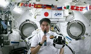 20日、国際宇宙ステーションで記者会見する大西卓哉飛行士。手前右に浮いているのは船内撮影用ロボット「イントボール2」(JAXAの中継から)