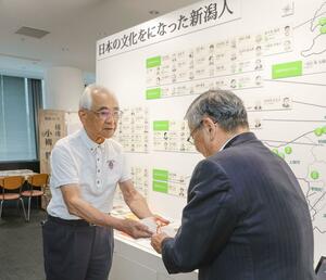 良寛会の長谷川義明理事長(左)から目録を受け取るにいがた文化の記憶館の小田敏三理事長=新潟市中央区
