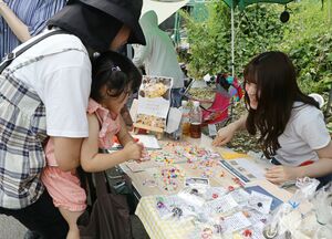 認知症の当事者らが手作りしたビーズのアクセサリーを選ぶ親子連れ=22日、新潟市北区松浜本町4