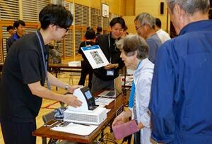 防災訓練で開設された避難所で、デジタル技術を活用したシステムに情報を登録する住民(右)ら=5日午前、石川県珠洲市