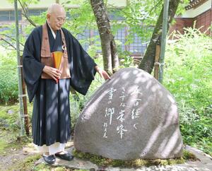 柿崎米峰俳句会が建立した句碑の横に立つ石黒英進さん=上越市柿崎区の楞厳寺