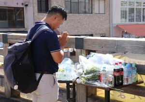　大阪・道頓堀のビル火災で、現場付近に設置された献花台に花を供え手を合わせる男性＝１９日午後