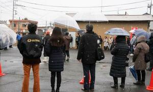 　雪が降る中、候補者の街頭演説に耳を傾ける人たち＝７日午後、茨城県行方市