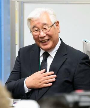 笑顔で集会後の取材に応じる阪原弘次さん=25日午後、国会