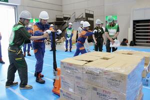 支援物資を移動するため、ハンドリフトの操作を体験する三条市立大の学生ら=三条市須頃1