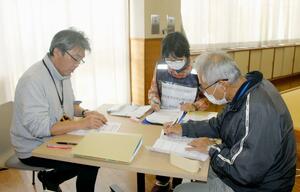 被災者への個別訪問前に、打ち合わせをするささえあいセンターの担当者たち=新潟市西区緒立流通2