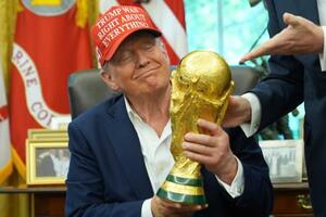 サッカーW杯組み合わせ抽選の日程発表で、優勝トロフィーを手にするトランプ大統領=22日、ワシントン(AP=共同)