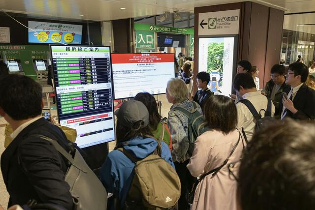 地震の影響で東北新幹線が運転を見合わせ、電光掲示を見る人たち＝２０日午後７時１６分、ＪＲ仙台駅