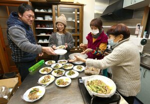地域の人のために料理を用意する安田和弘さん(左)と妻の真生未さん(左から2人目)=1月26日、石川県七尾市