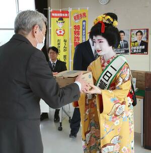 一日署長を務め、当選者に防犯機能付き電話機を手渡す古町芸妓の「いち弥」さん=新潟北署