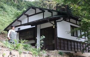 一棟貸しの宿に改装する民家。準備を進める堀田弥生さんは「石垣や林を整備し、すてきな景観に仕上げたい」と語る=佐渡市相川中京町
